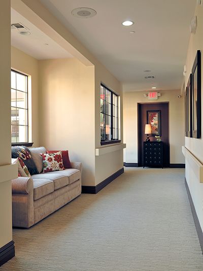 A cozy hallway with a sofa and decorative pillows near large windows.