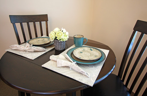A beautifully arranged dining table featuring elegant plates, a coffee mug, and a charming floral centerpiece.