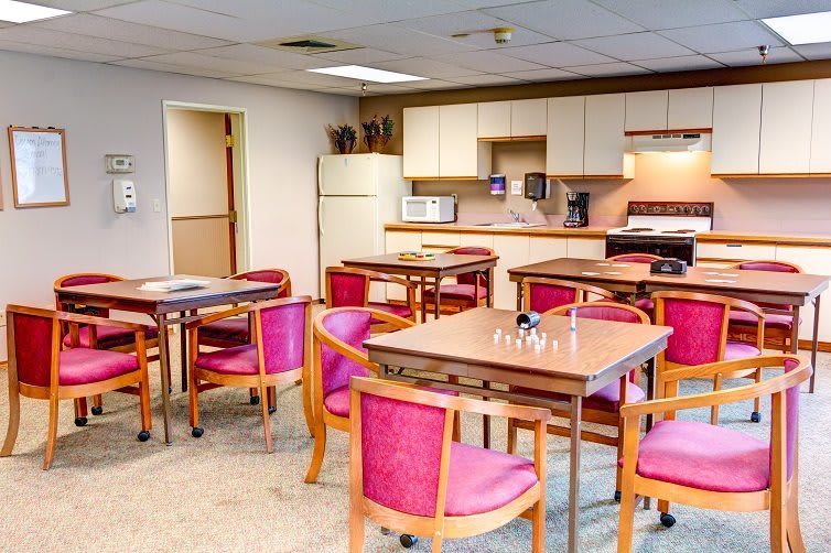 A cozy lounge area with tables and chairs adjacent to a small kitchen space.
