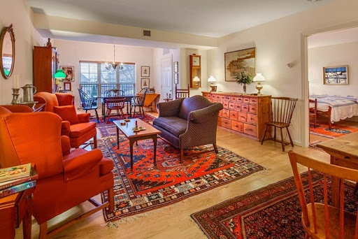 A beautifully arranged living room featuring red upholstered chairs, a dark sofa, and an elegant rug, creating a warm and inviting atmosphere.