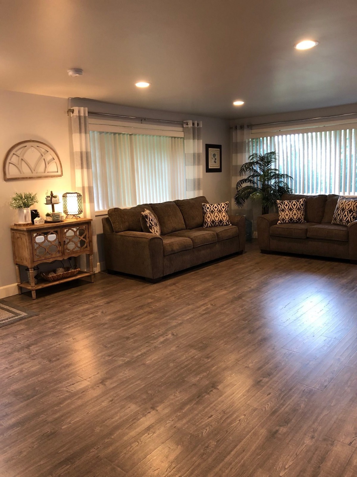 A cozy living room with two sofas, warm lighting, and hardwood floors.