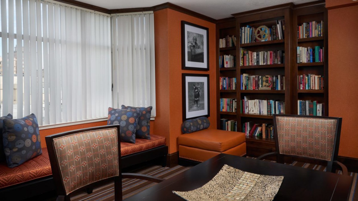 A cozy reading nook with a bookshelf filled with books and comfortable seating in a warmly decorated room.
