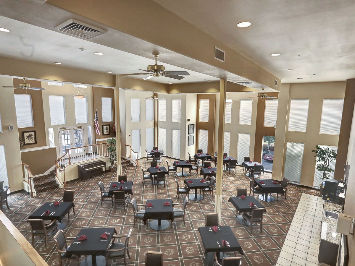 Spacious dining area with neatly arranged tables and chairs, featuring large windows for natural light.