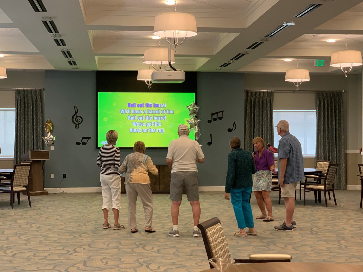 Seniors enjoying a group karaoke session in a community center.