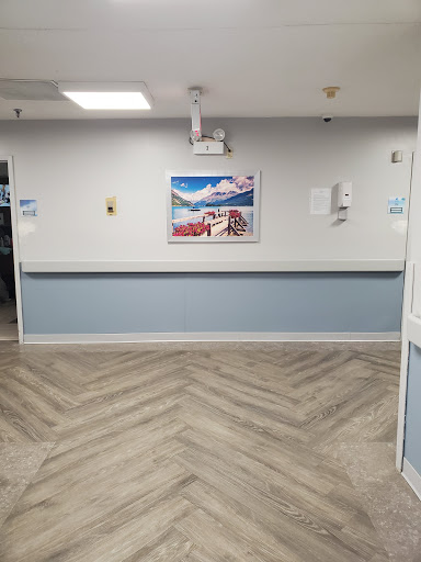 A view of a hospital corridor featuring an artwork on the wall and a patterned floor.