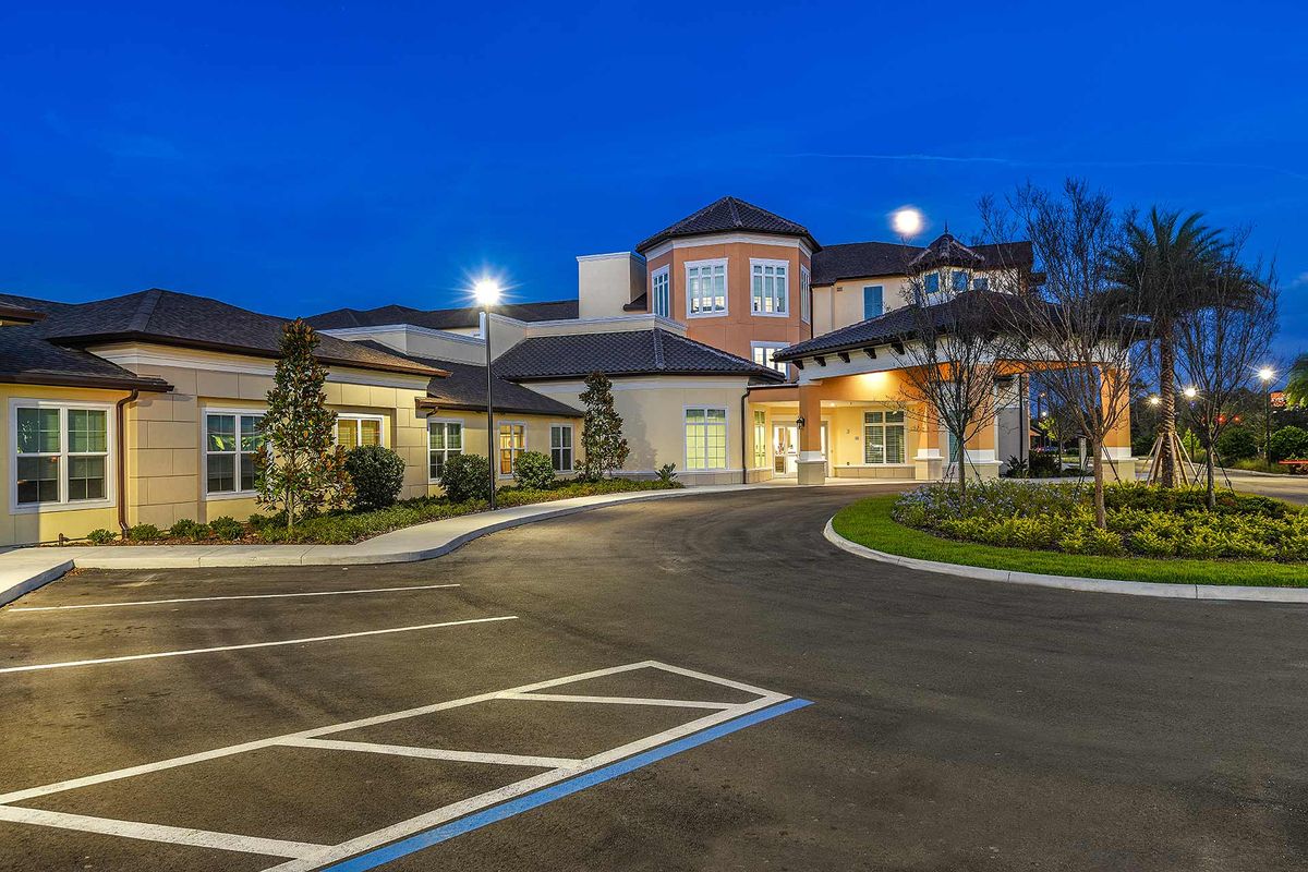 A well-lit building with a parking lot at night.