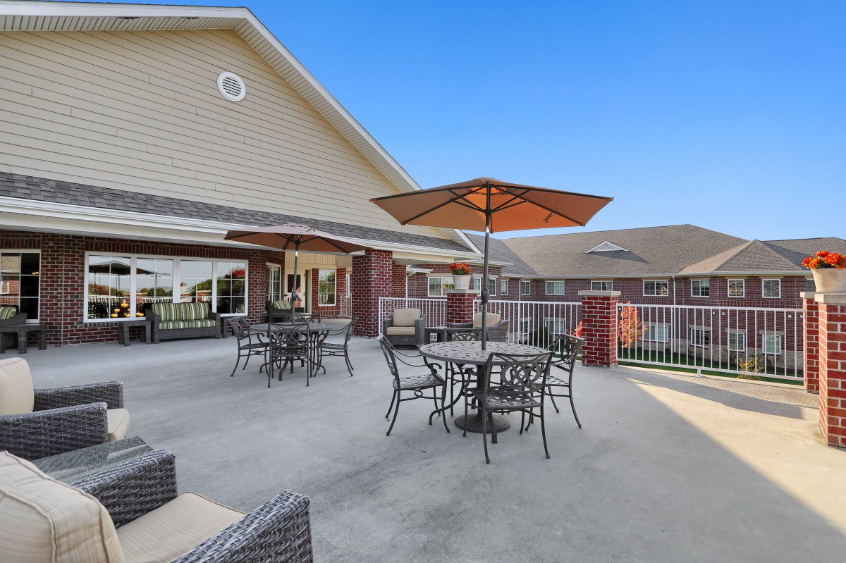 An outdoor patio area with tables, chairs, and umbrellas next to a building.