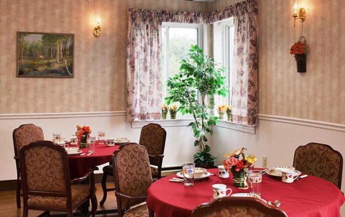 A cozy dining room with elegantly set tables and floral decorations.