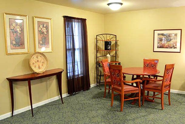 A cozy dining room featuring a wooden table with chairs, decorative shelves, and warm lighting.