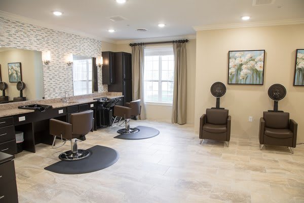 A well-lit and modern salon interior with stylist stations and hair dryer chairs.