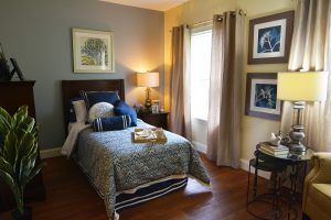 A cozy bedroom with a single bed, decorative pillows, and framed art on the walls.