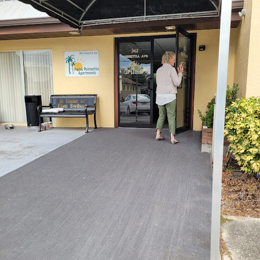 A woman approaching the entrance of a building, with a bench visible nearby.