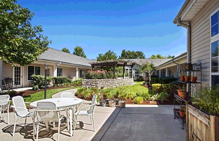 A tranquil courtyard with outdoor seating and a well-maintained garden on a sunny day.