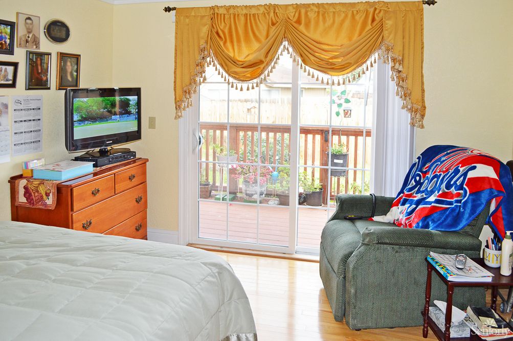 A cozy bedroom with a television, an armchair, and sliding doors leading to a deck.
