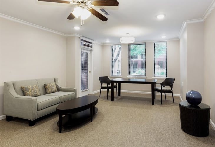 A modern living room with a sofa, table, chairs, and large windows.