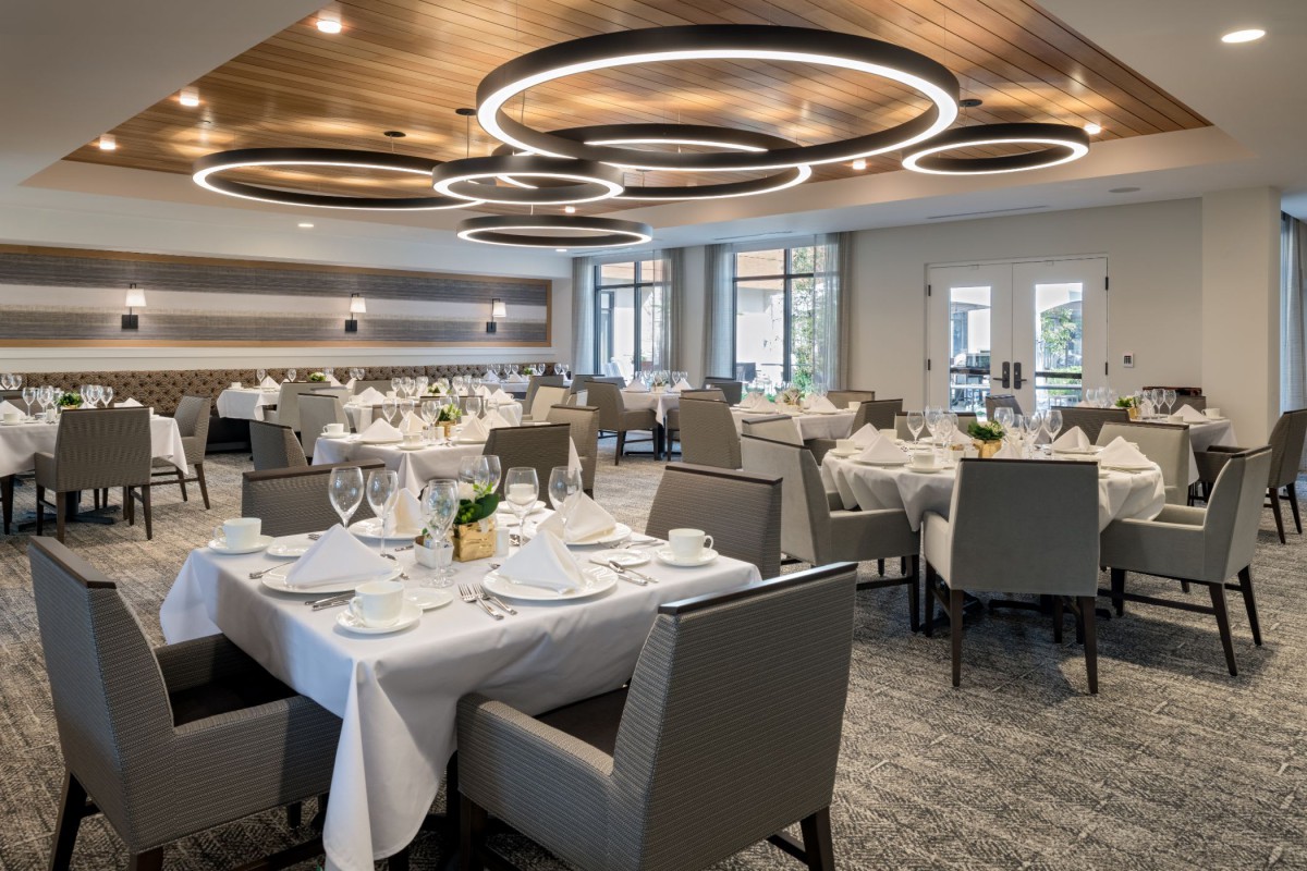 A modern and elegantly designed dining area with neatly arranged table settings and unique ceiling lights.