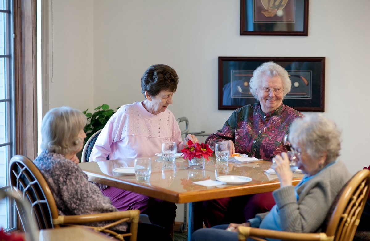 A group of seniors socializing around a dining table.