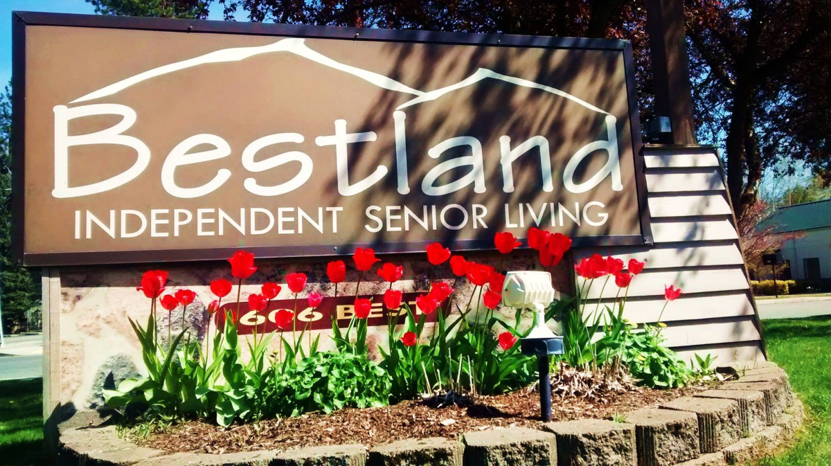 Sign for an independent senior living community surrounded by red tulips.