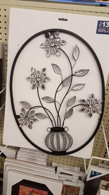 Metal wall art featuring a floral design with a vase.
