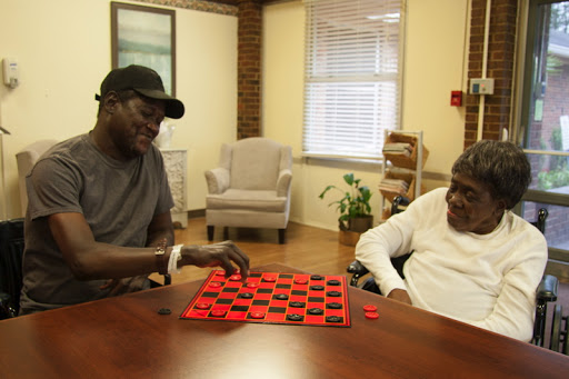 Two individuals enjoying a game of checkers in a cozy indoor setting.