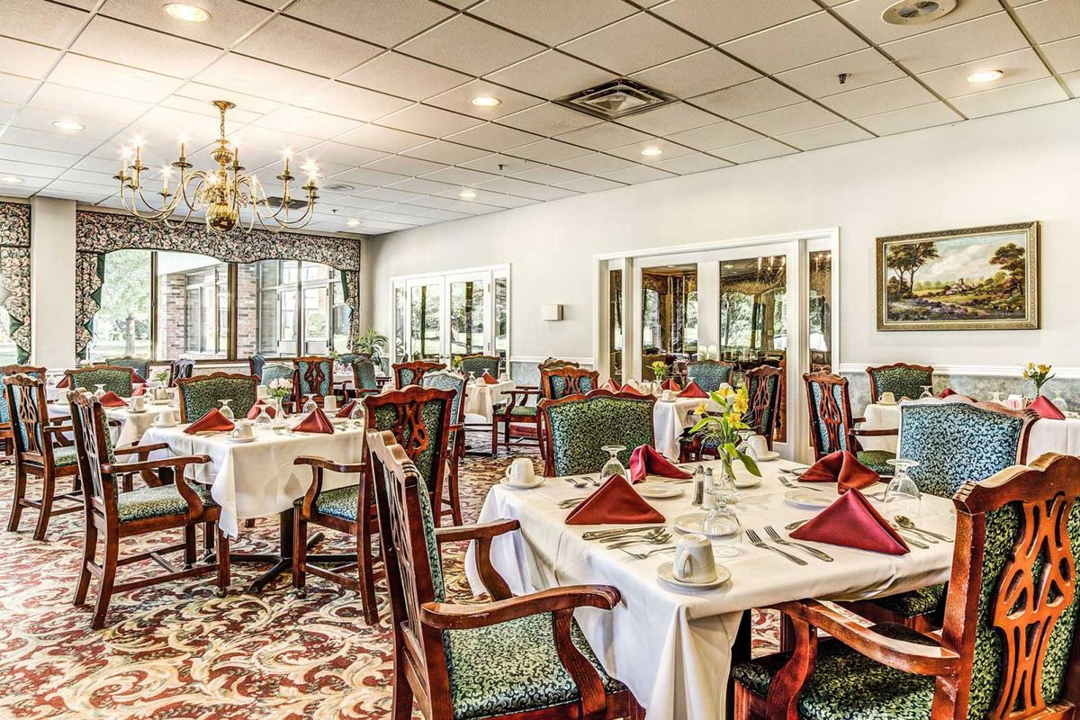 An elegant restaurant dining room with neatly set tables and a chandelier overhead.