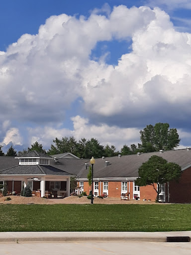 A scenic view of a modern building surrounded by green grass, under a cloudy sky.