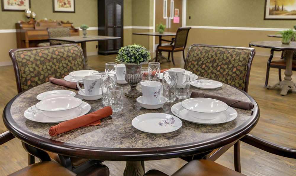 A well-set dining table with plates, cups, and a potted plant.