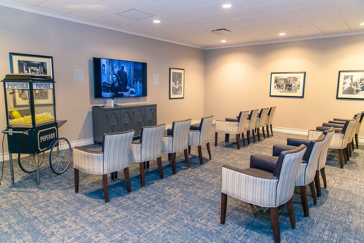 A cozy home theater setup with multiple rows of chairs facing a large television.