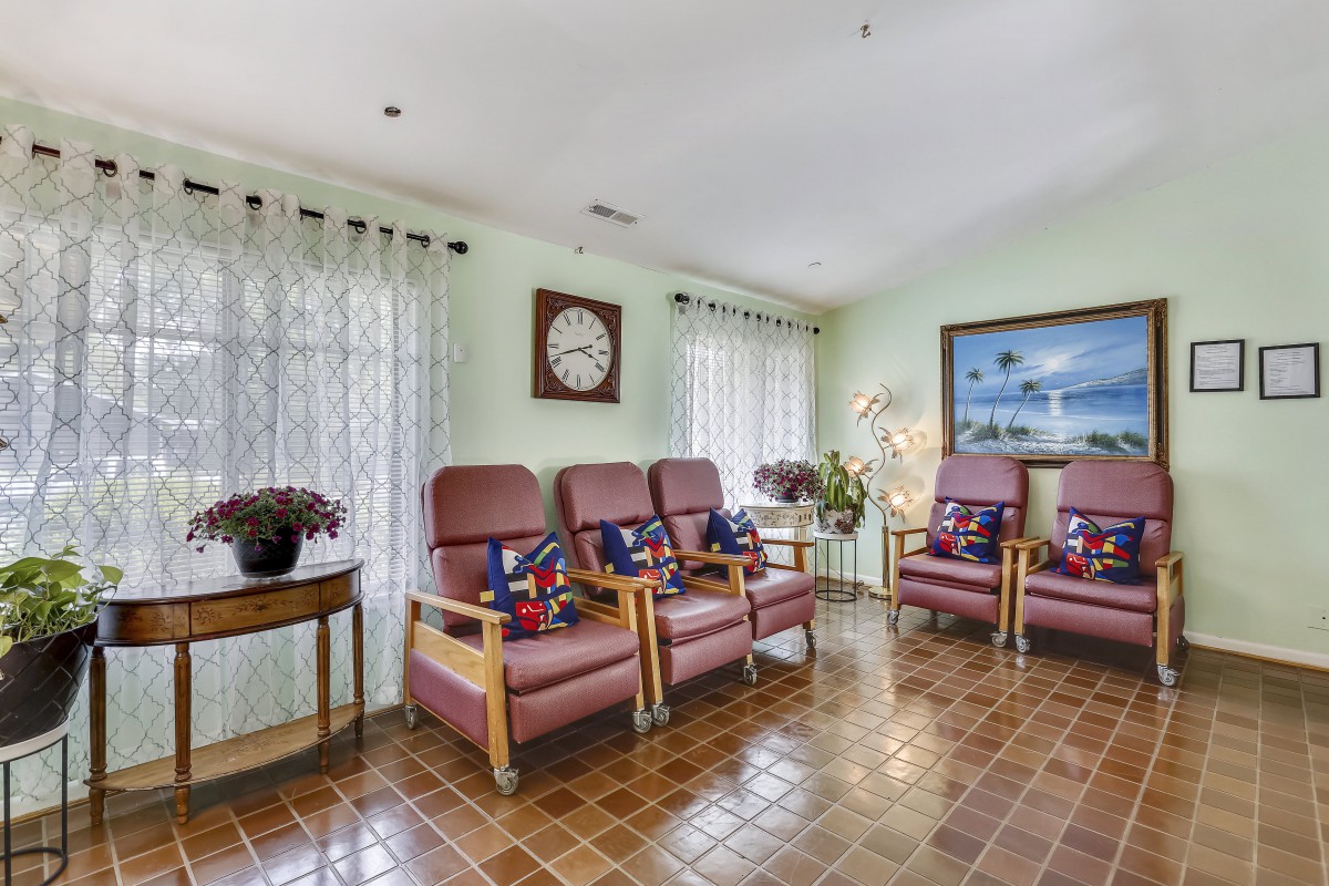 A cozy waiting room featuring comfortable chairs, a decorative clock, and a serene painting on the wall.