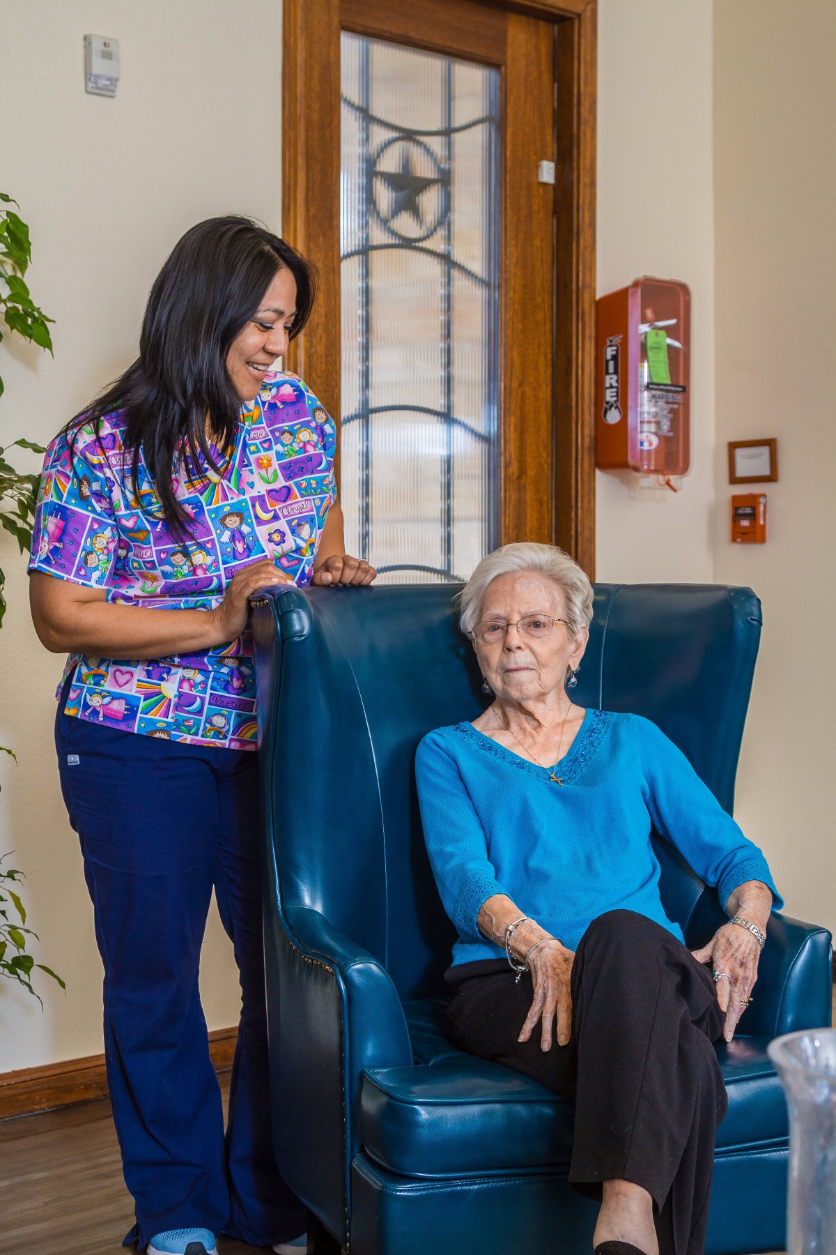 A nurse provides care and companionship to an elderly woman in a comfortable setting.