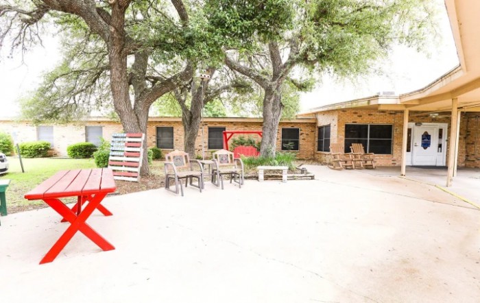 An outdoor patio area with seating under large trees.