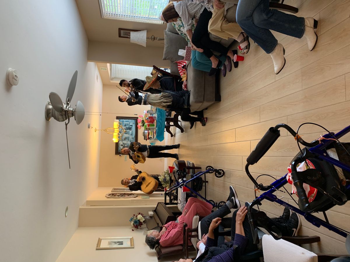 A group of people gathered in a living room, enjoying music played on a guitar.