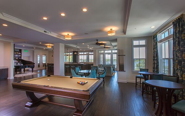 A modern game room featuring a billiards table and comfortable seating with ample natural light.