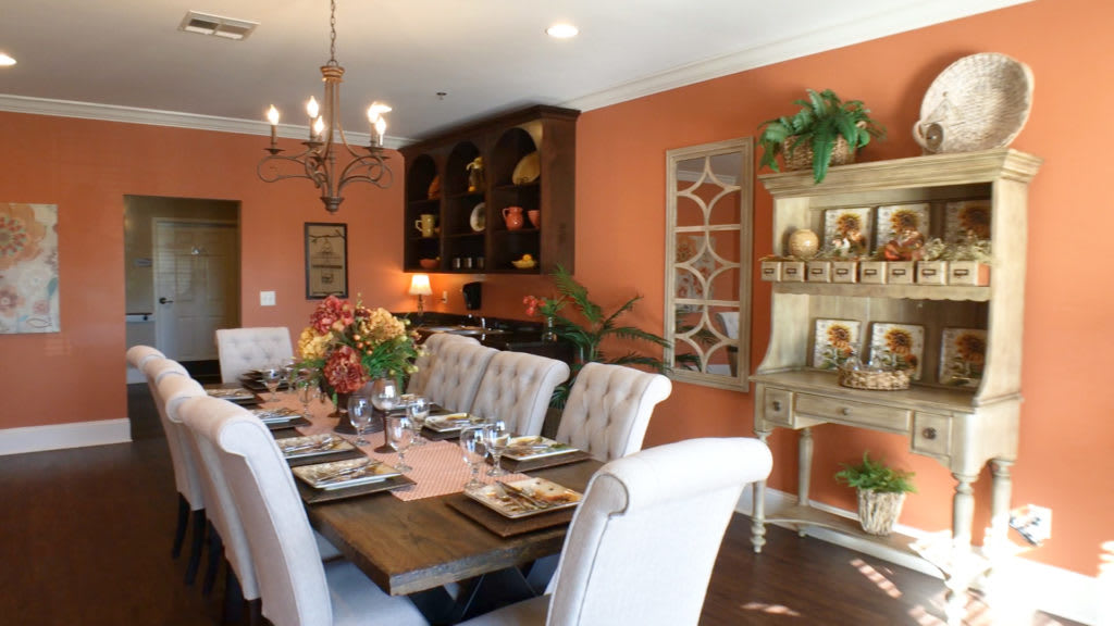 A beautifully decorated dining room with orange walls and an elegant table setting.
