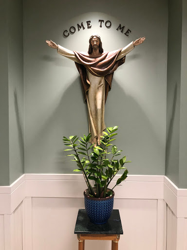 A serene indoor setting featuring a religious statue and a decorative plant.