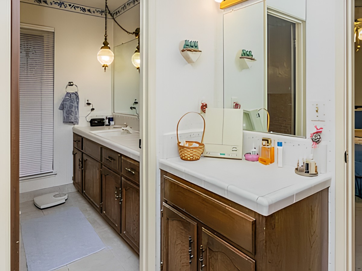 A spacious bathroom with dual sinks, wooden cabinets, and elegant lighting.