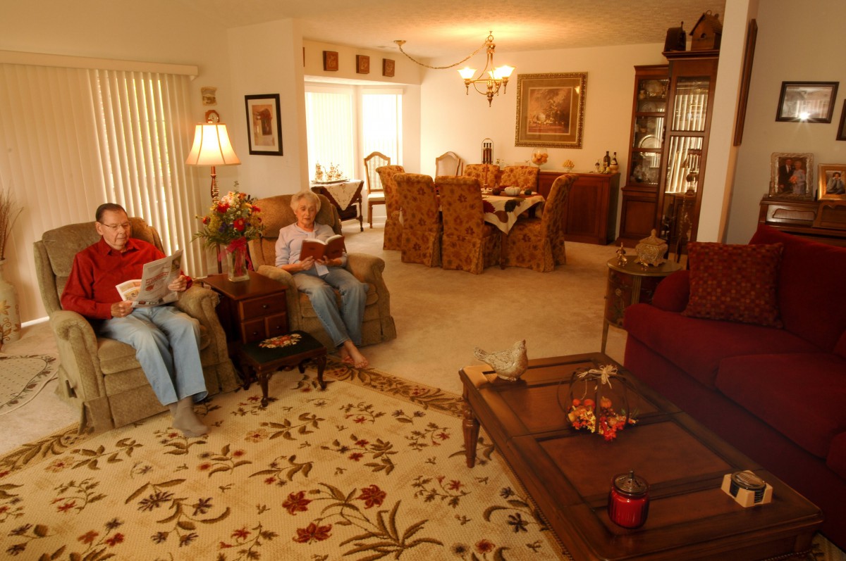A cozy living room with a dining area in the background, where people are relaxing and reading.