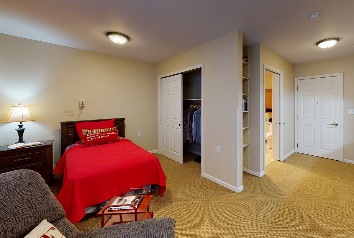 A cozy bedroom with red bedding and an open closet.