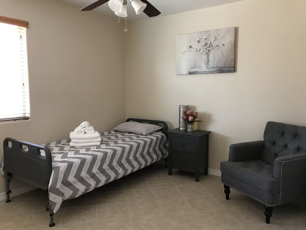 A minimalist bedroom with a single bed, gray-toned decor, and a cozy armchair.