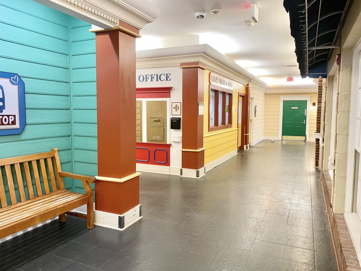 A brightly colored hallway with a bench and office entrance.