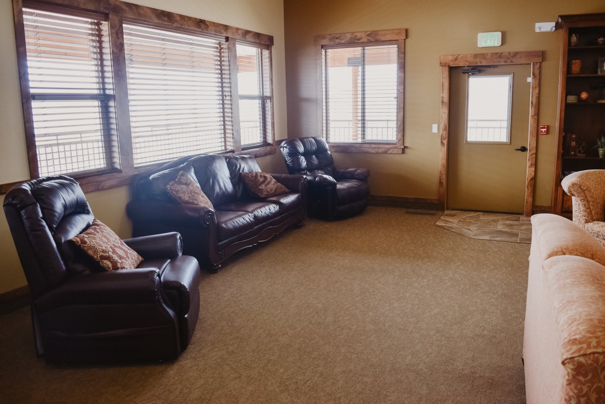 A cozy living room with leather seating and large windows.