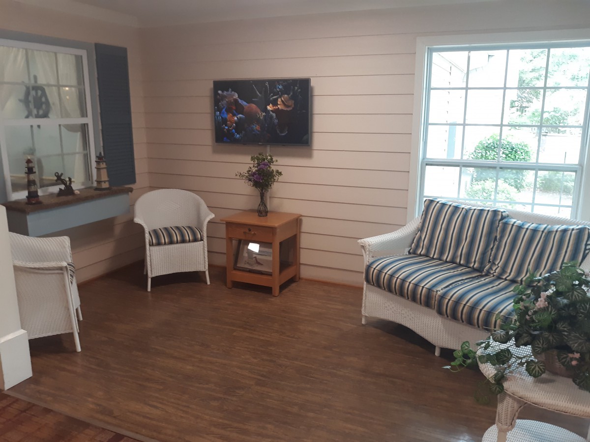 A cozy living room setup with armchair and sofa near a window.