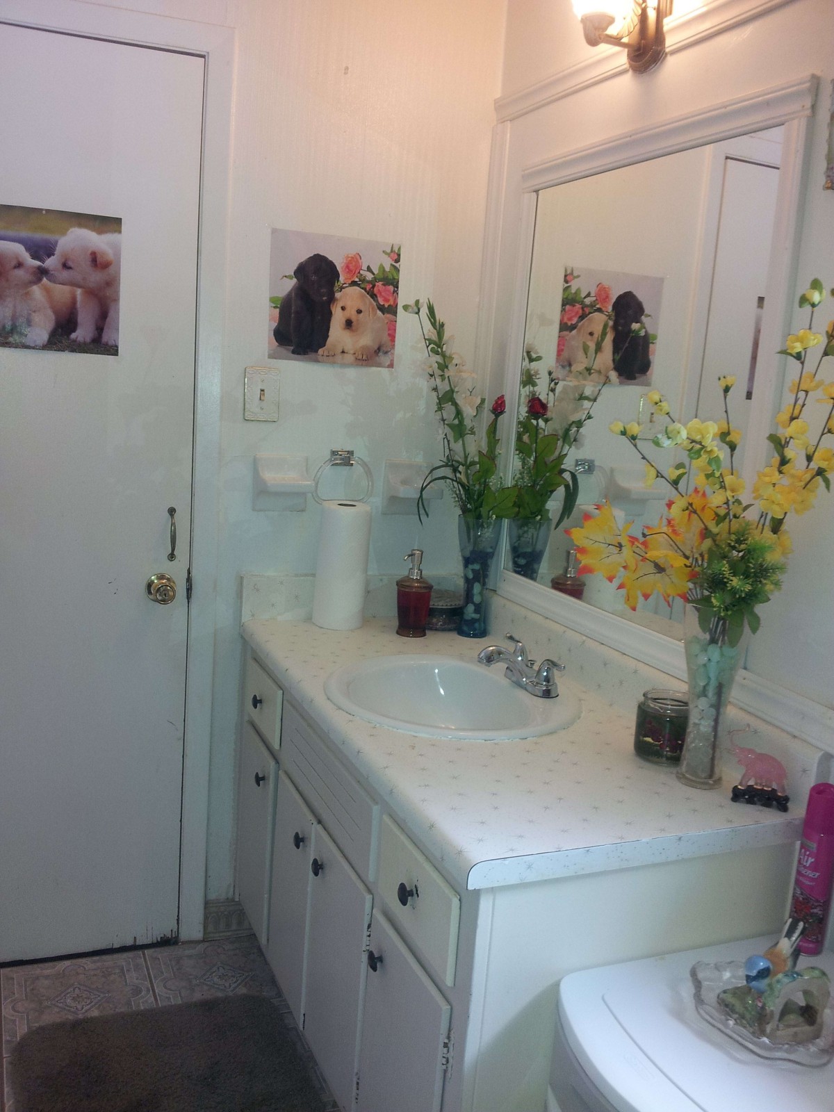 A neatly arranged bathroom with a sink, mirror, and floral decorations.