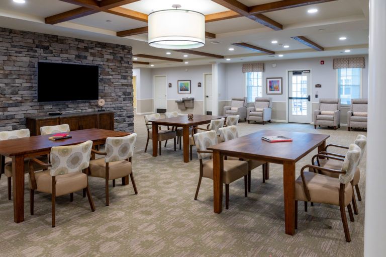 A modern dining and living space featuring wooden tables, comfortable chairs, and warm lighting.