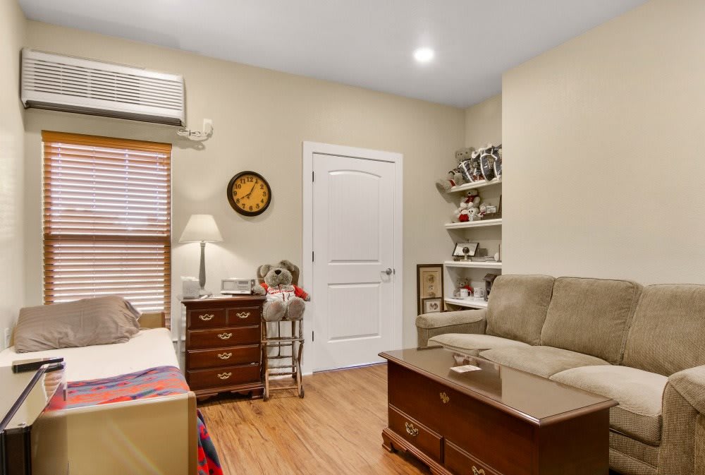 A cozy living room with a couch, coffee table, and bookshelves, complemented by warm wooden flooring and a lamp.