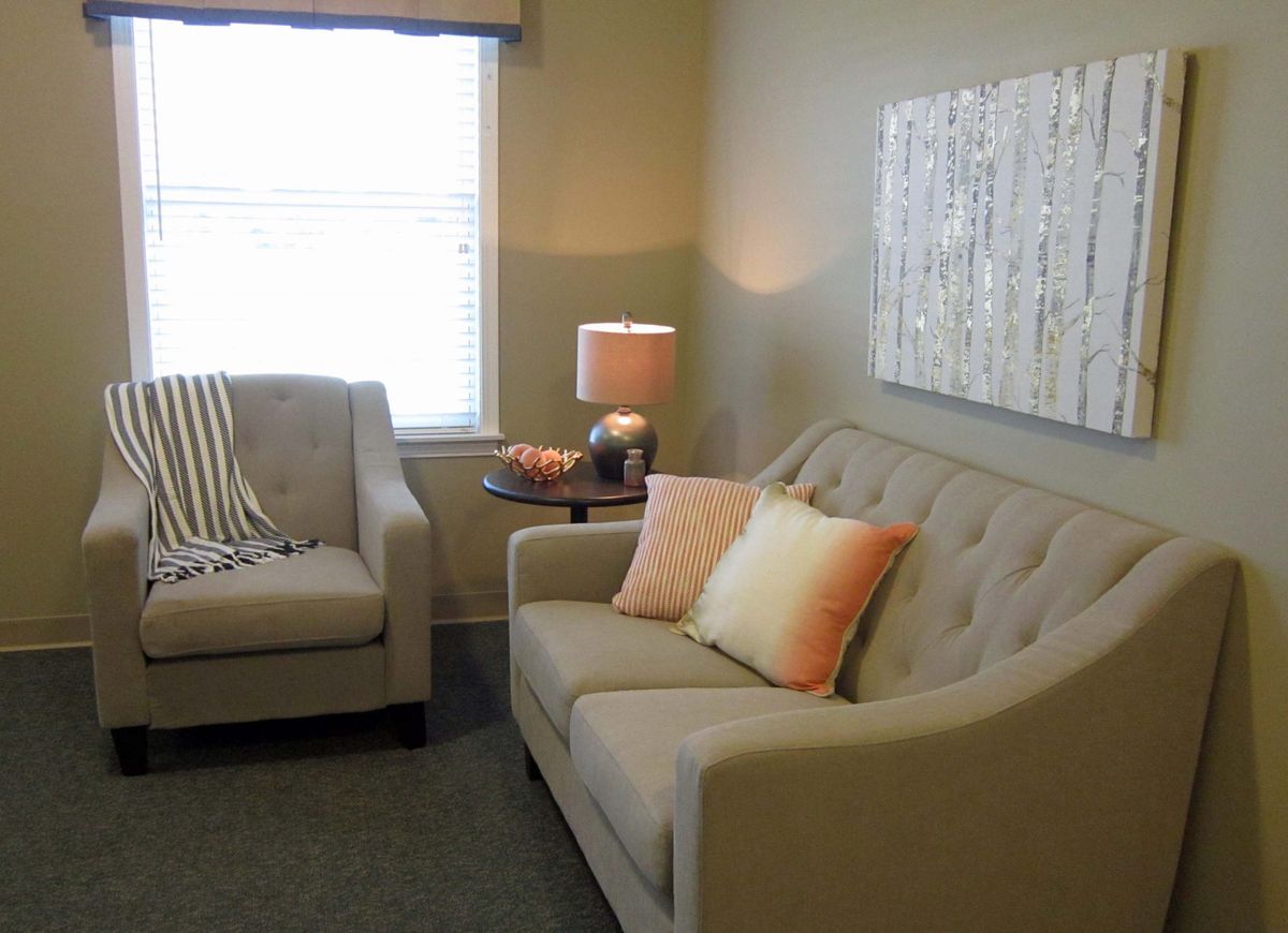 A cozy living room with sofas, cushions, and a warm lamp.