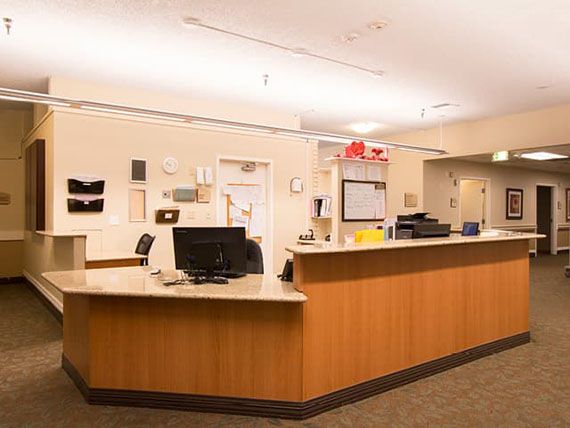 A reception desk in a well-lit office environment, featuring computers and organized workspace.