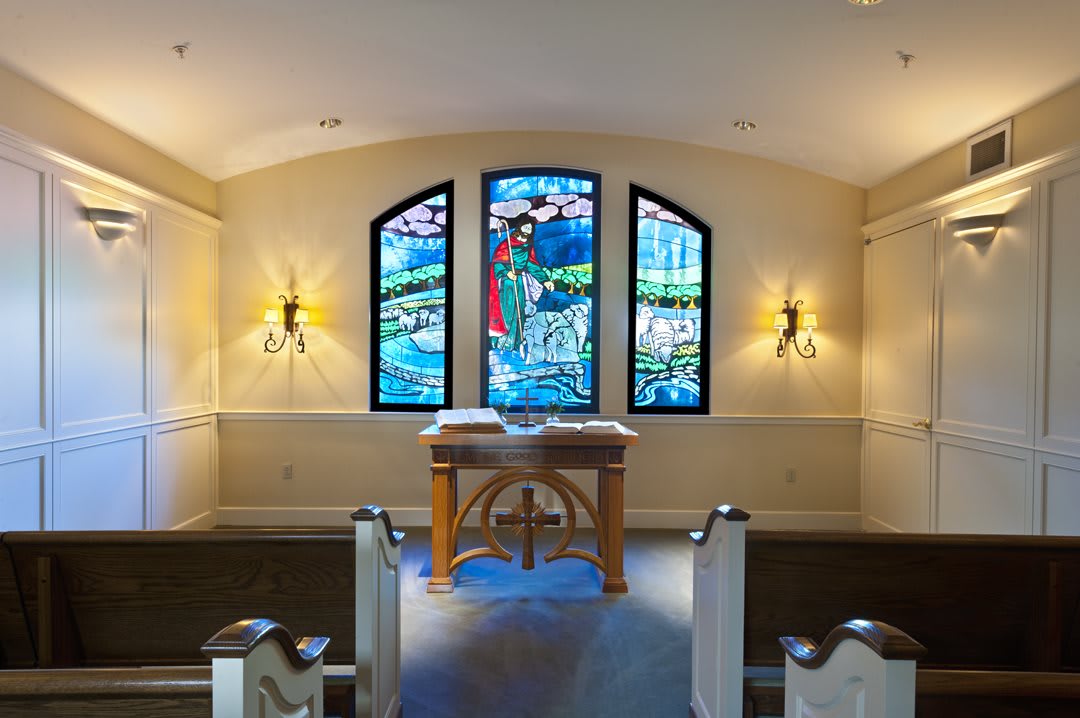 A serene chapel interior featuring stained glass windows and a wooden altar.