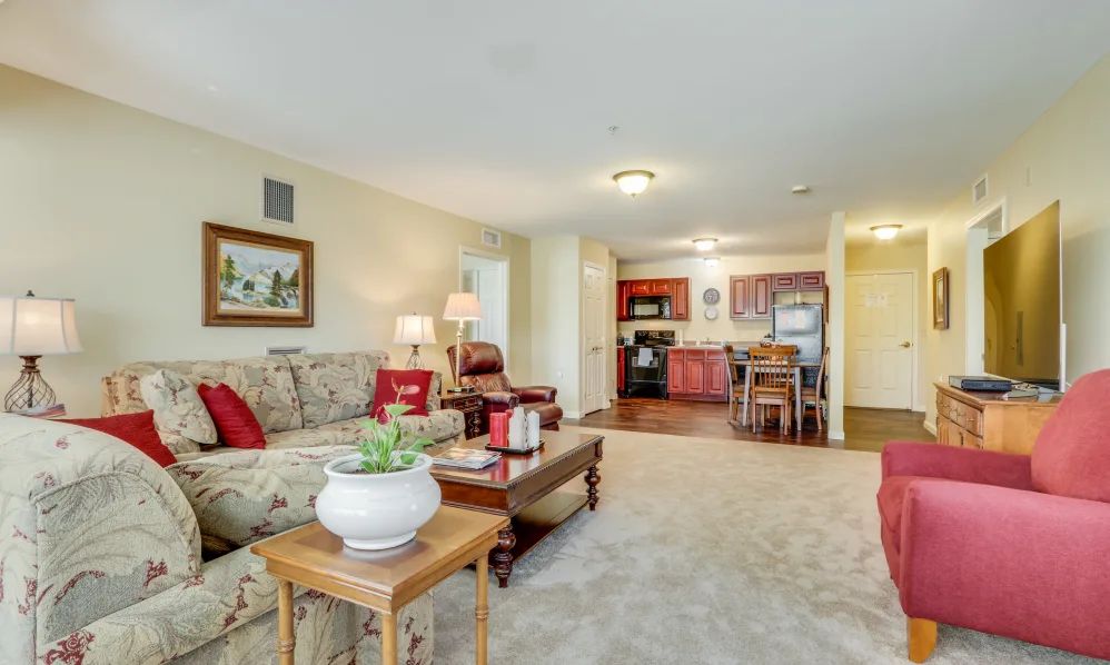 A cozy living room with a sofa and coffee table, transitioning into a kitchen area in an open floor plan.