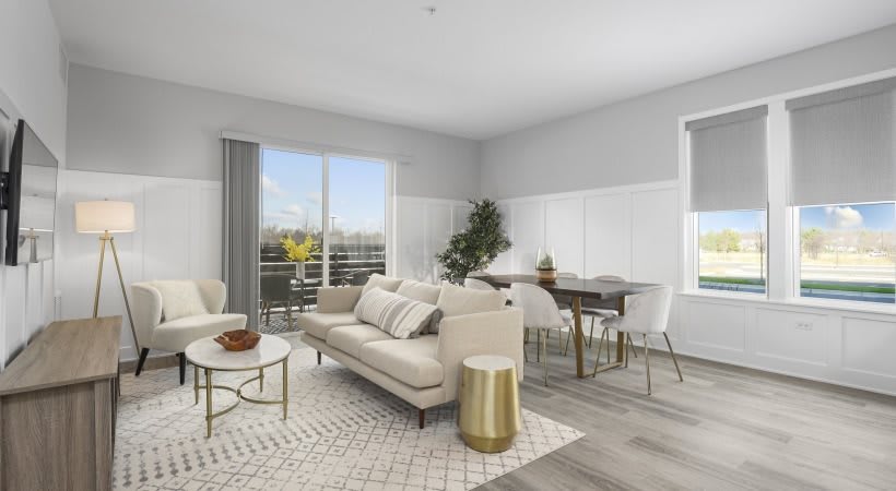 A modern living room with a cozy sofa, coffee table, and an adjacent dining area, decorated in neutral tones.